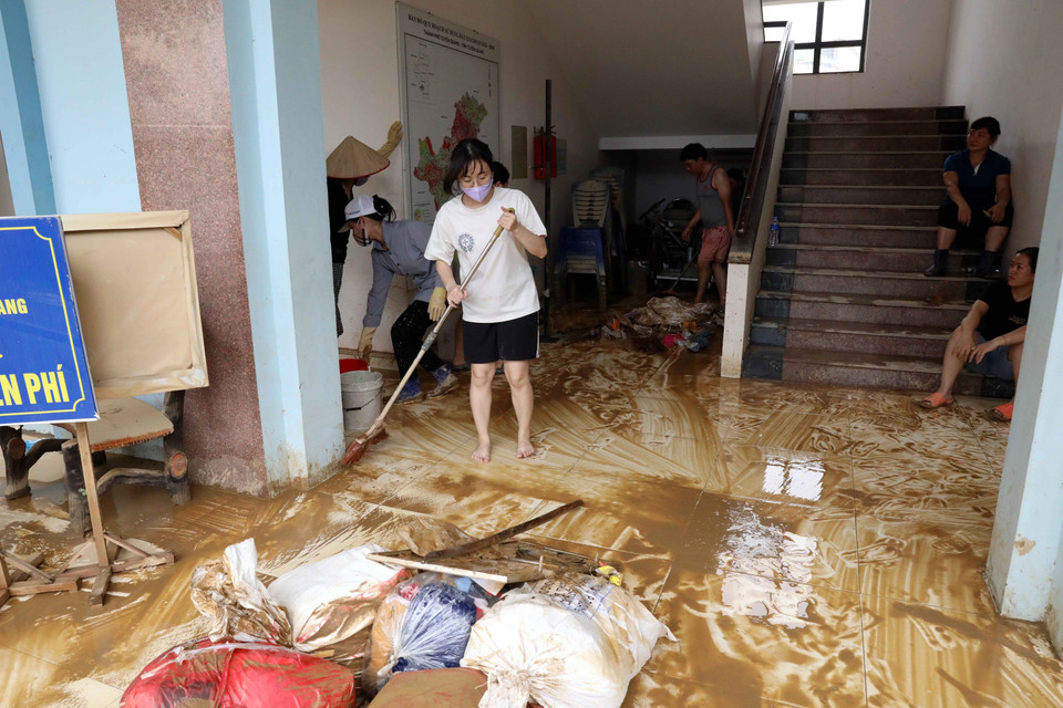 Cán bộ, nhân viên Ủy ban Nhân dân phường Tân Quang vệ sinh công sở ngay sau khi nước rút. (Ảnh: Quang Cường/TTXVN)