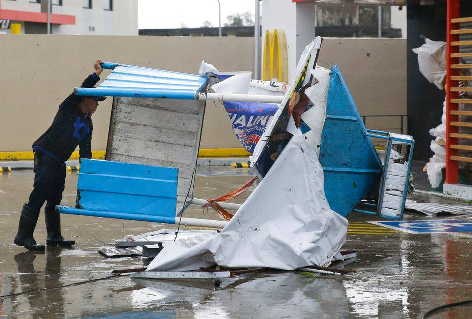 Một người đàn ông nhấc một trạm gác nhỏ sau khi nó bị lật bởi những cơn gió mạnh từ siêu bão Mangkhut. (Nguồn: AP)