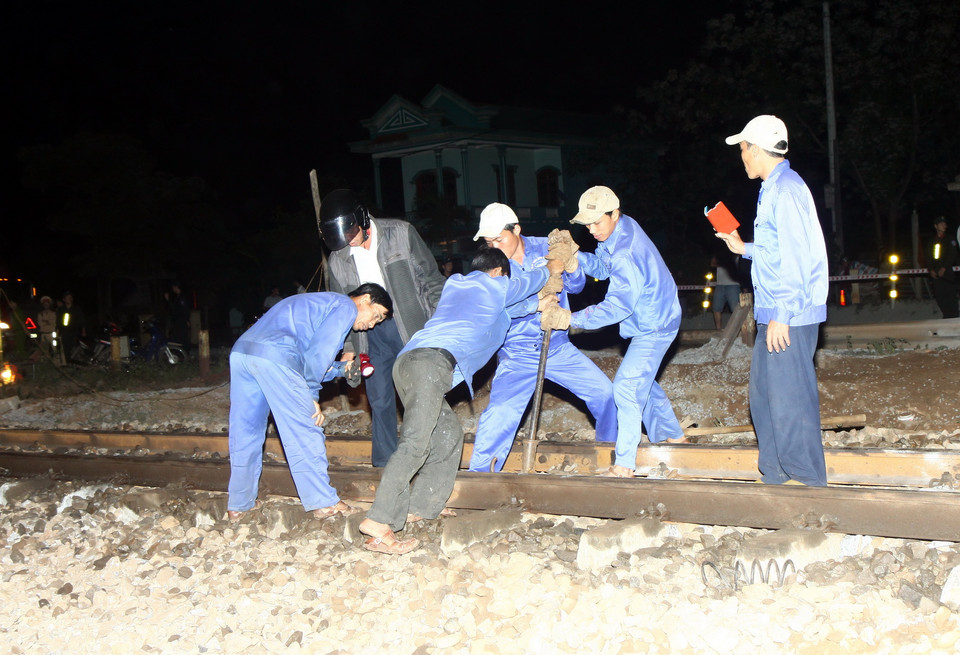 Ngành đường sắt đã huy động công nhân khắc phục hư hỏng trên tuyến giao thông đường sắt và đảm bảo an toàn giao thông trên tuyến Quốc lộ 1A. (Ảnh: Hồ Cầu/TTXVN)