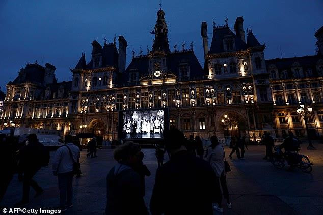 Mọi người đi bộ trên quảng trường Tòa thị chính của Paris ngày 26/9, nơi một màn hình khổng lồ được dựng lên chiếu hình ảnh của cựu Tổng thống Pháp Jacques Chirac. (Nguồn: AFP)