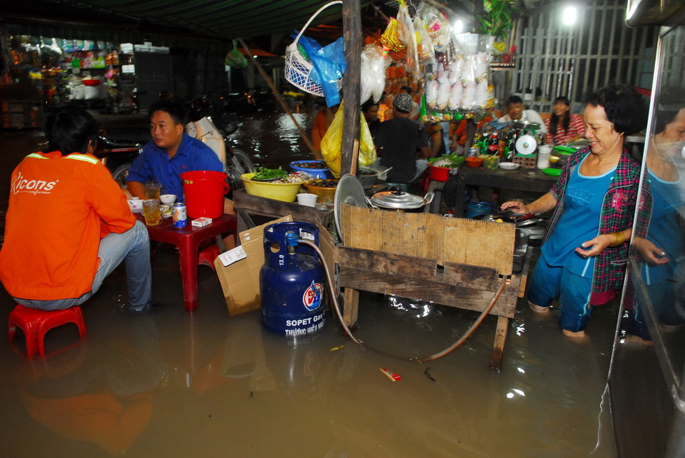 Quán ốc của bà Huỳnh Thị Mười (60 tuổi, xã Phước Kiểng, huyện Nhà Bè) chìm trong biển nước. (Ảnh: Mạnh Linh/TTXVN) 