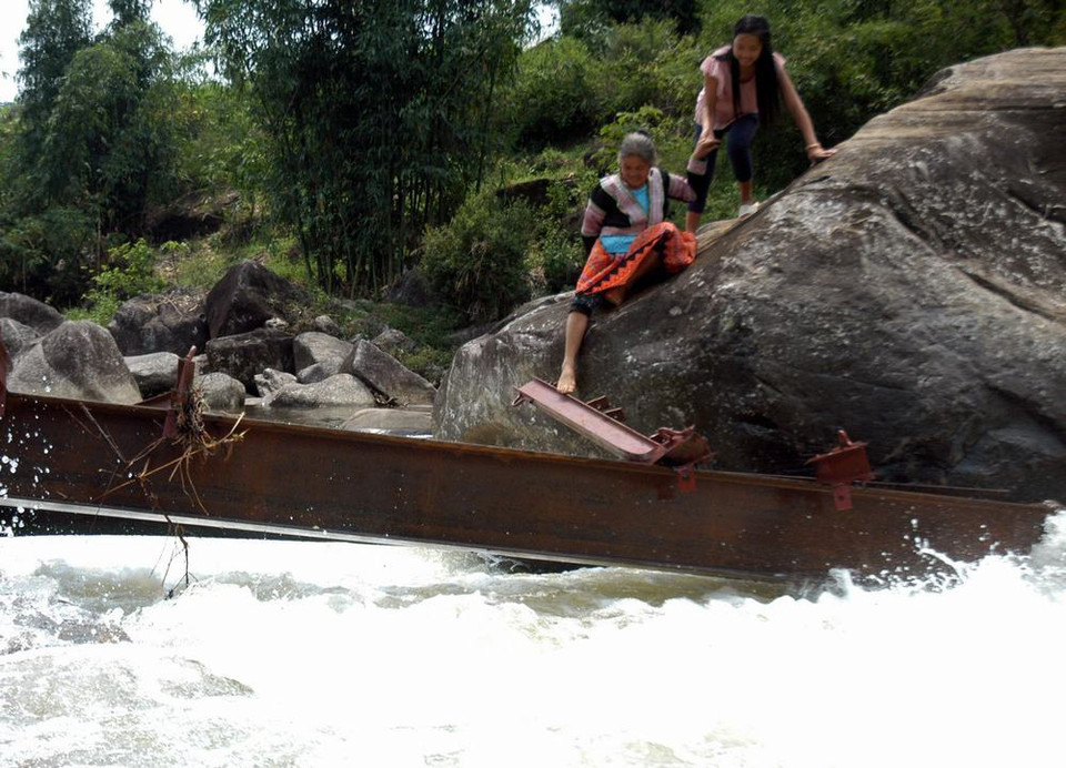  Người dân Chu Va 6 vượt qua suối trên những thanh sắt cầu tạm vừa bị lũ cuốn trôi rất nguy hiểm đến tính mạng. (Ảnh: Nguyễn Công Hải/TTXVN)