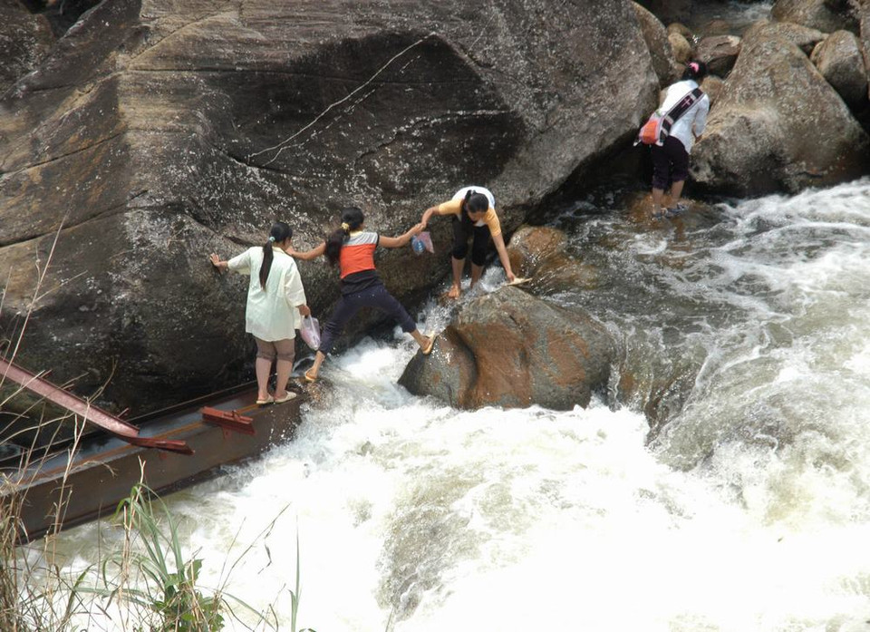 Người dân Chu Va 6 vượt qua suối trên những thanh sắt cầu tạm vừa bị lũ cuốn trôi rất nguy hiểm đến tính mạng. (Ảnh: Nguyễn Công Hải/TTXVN)