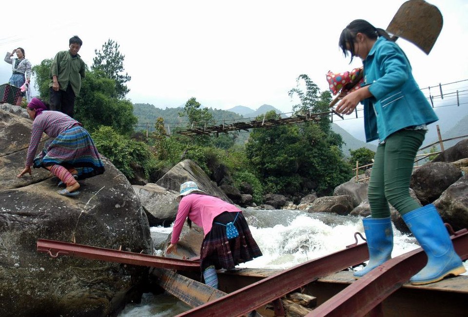 Người dân Chu Va 6 vượt qua suối trên những thanh sắt cầu tạm vừa bị lũ cuốn trôi rất nguy hiểm đến tính mạng. (Ảnh: Nguyễn Công Hải/TTXVN)