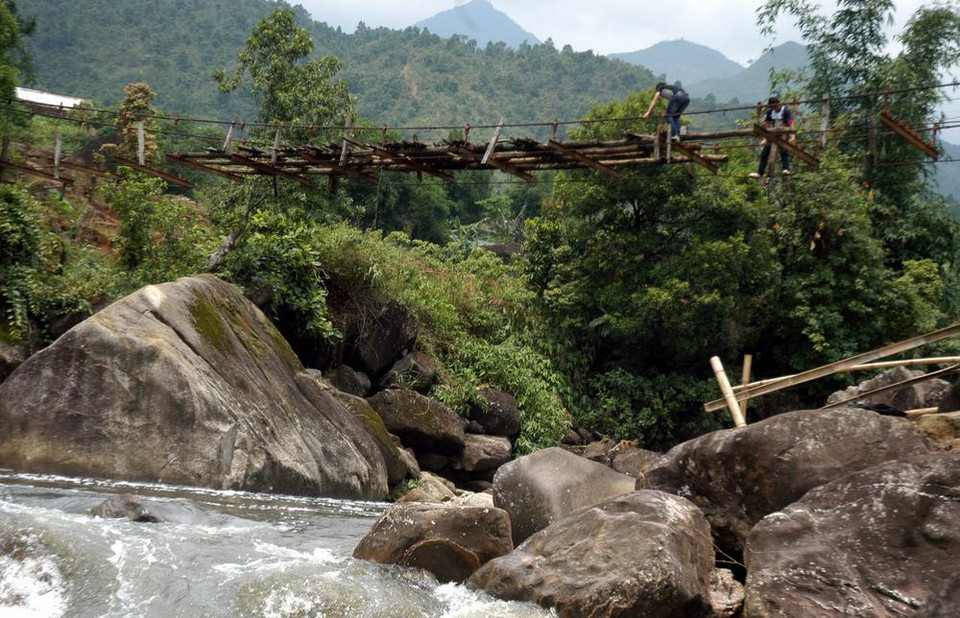 Nhiều người dân vượt qua suối trên chiếc cầu treo cũ nát bỏ hoang rất nguy hiểm. (Ảnh: Nguyễn Công Hải/TTXVN)