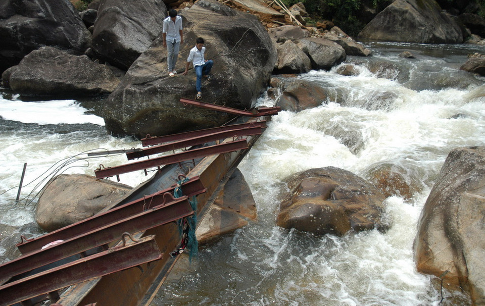 Người dân Chu Va 6 vượt qua suối trên những thanh sắt cầu tạm vừa bị lũ cuốn trôi rất nguy hiểm đến tính mạng. (Ảnh: Nguyễn Công Hải/TTXVN)