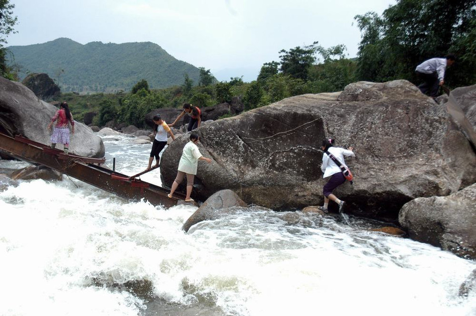 Người dân Chu Va 6 vượt qua suối trên những thanh sắt cầu tạm vừa bị lũ cuốn trôi rất nguy hiểm đến tính mạng. (Ảnh: Nguyễn Công Hải/TTXVN)