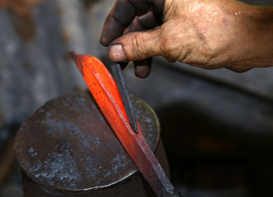 Người thợ rèn cho một miếng thép nhỏ vào giữa tạo cho lưỡi dao sắc bén lâu dài. (Ảnh: Duy Khương/TTXVN)