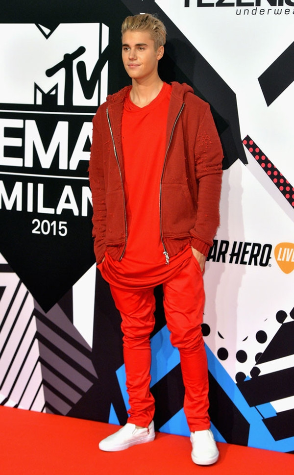 Justin Bieber xuất hiện khá thoải mái với trang phục tông đỏ chủ đạo, áo khoác có mũ (hoodie) kết hợp cùng đôi giày trắng của Vans.