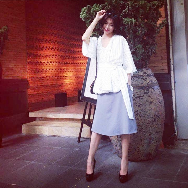 Quỳnh Châu có chút khác lạ khi phối thiết kế chân váy midi xanh phấn và áo đai quấn (wrap top) mang phom dáng áo ngủ khi xuống phố.