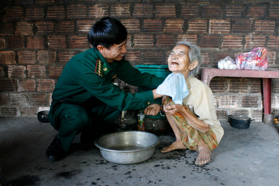 Chiến sỹ Đội công tác địa bàn đồn biên phòng Đăk Xú, Kon Tum thăm và chăm sóc cho bà Y Dên, 1 trong 2 cụ già neo đơn đang được Đồn biên phòng nhận chăm sóc. (Ảnh: Hồng Điệp/TTXVN)