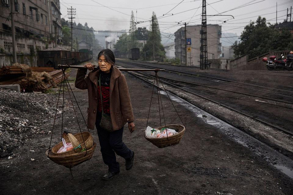 Người phụ nữ mang hàng hóa ra bán tại chợ từ ga Shixi. (Ảnh: Kevin Frayer/Ibtimes)