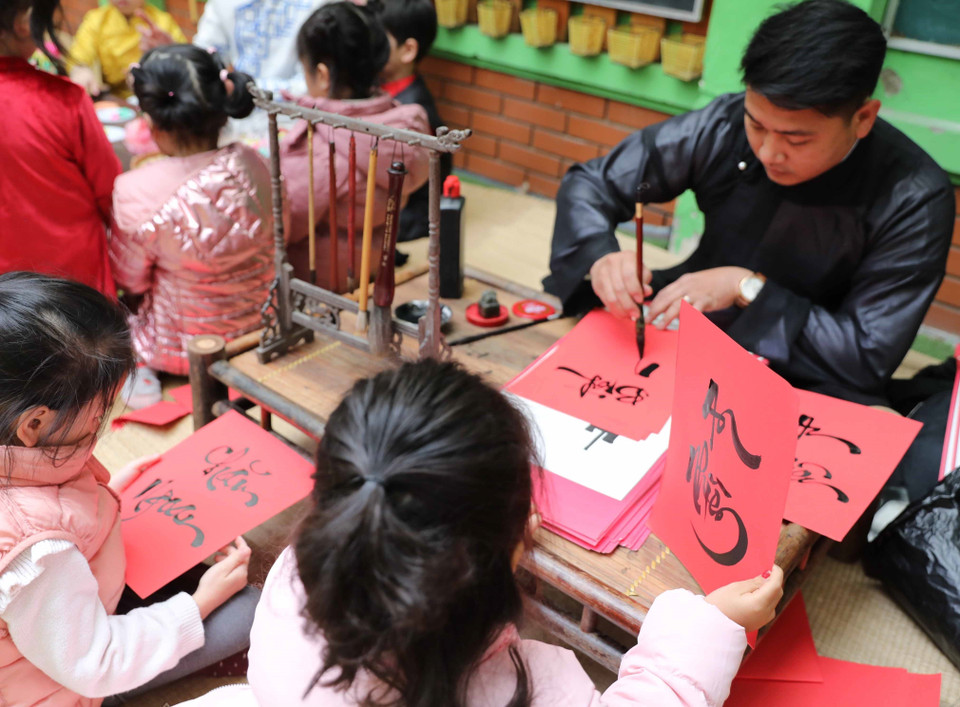 Trẻ được tìm hiểu, xem ông đồ viết chữ ngày Xuân. (Ảnh: Thanh Tùng/TTXVN)