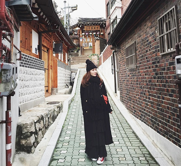 Cũng chọn váy xếp tầng tương tự Yến Trang, nhưng Yến Nhi kết hợp linh hoạt nhiều lớp cùng áo khoác trench màu tối. Mũ len và khăn quàng là phụ kiện giữ ấm và tăng nét phóng khoáng cho nữ ca sỹ.