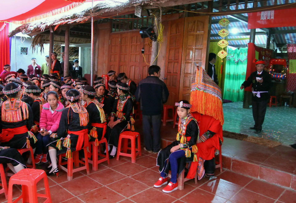 Cô dâu (chùm đầu) ngồi trước cửa nhà chú rể để thầy cúng thực hiện các nghi thức trong lễ cưới. (Ảnh: Thế Duyệt/TTXVN)