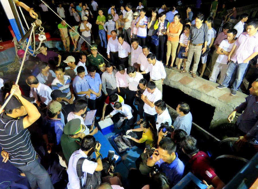 Người dân chứng kiến cơ quan chức năng, kiển tra, chứng thực nguồn gốc hải sản. (Ảnh: Thành-Thọ/Vietnam+)