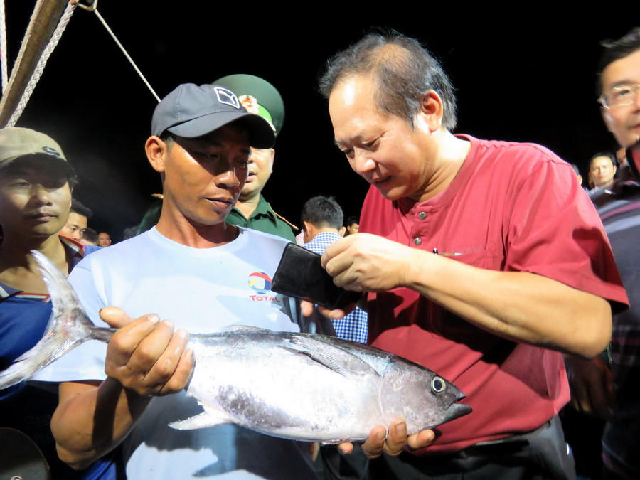 Bộ trưởng Trương Minh Tuấn đã móc ví mua cá ngừ được chứng minh nguồn gốc. (Ảnh: Thành-Thọ/Vietnam+)