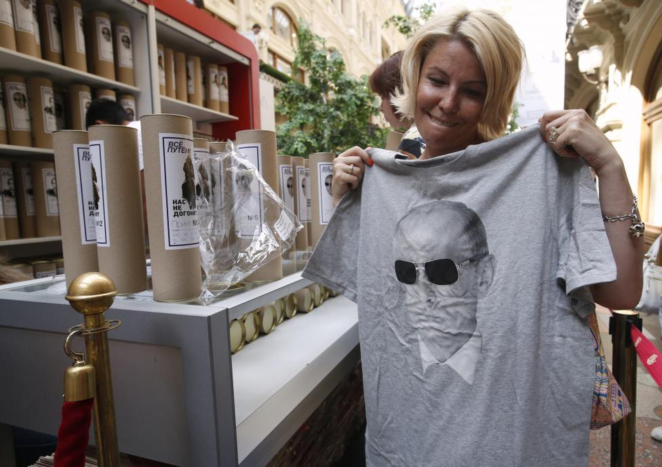 Một người phụ nữ cầm trên tay chiếc áo phông in hình của tổng thống Nga Vladimir Putin tại cửa hàng GUM nằm ở trung tâm Moscow. Bức ảnh được chụp vào ngày 11/8/1014. (Nguồn: REUTERS)