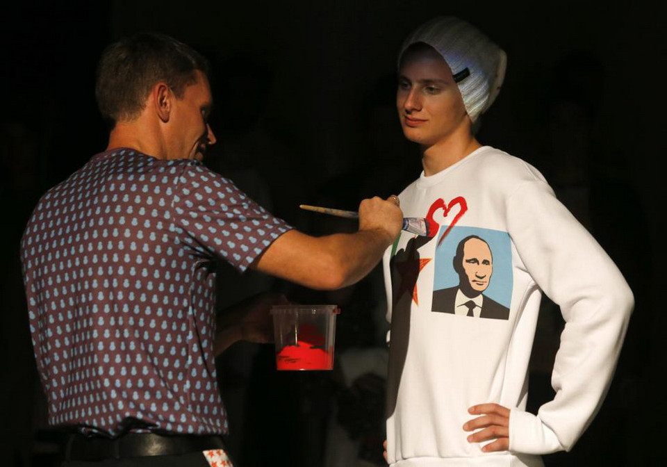 Nghệ sỹ Alexey Sergienko (Trái) vẽ một trái tim lên chiếc áo phông in hình Tổng thống Nga Putin trong buổi trưng bày của tuần lễ thời trang Homeland, được tổ chức nhằm kỷ niệm sinh nhật lần thứ 62 của ông Putin tại St. Petersburg vào ngày 7/10/2014. (Nguồn: REUTERS)
