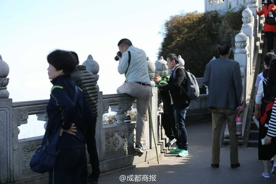 Một du khách vắt chân qua lan can để cố chụp một bức ảnh phong cảnh đẹp. (Nguồn: QQ News)