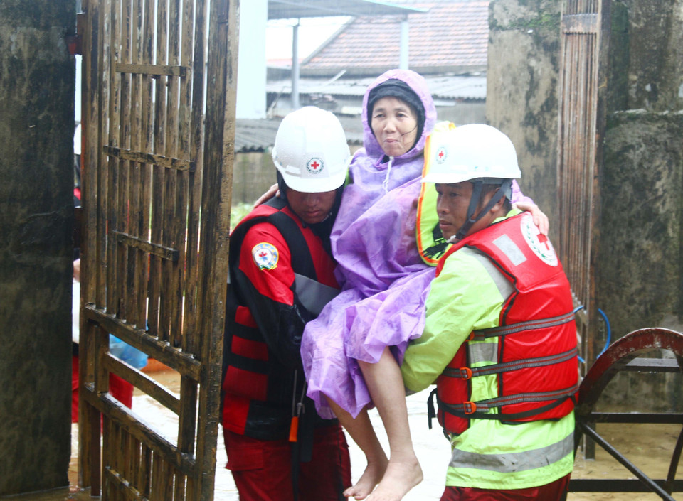 Đội cứu trợ hỗ trợ một người dân tại huyện Lệ Thủy (Quảng Bình) vừa điều trị từ bệnh viện trở về nhà. (Ảnh: Tá Chuyên/TTXVN)