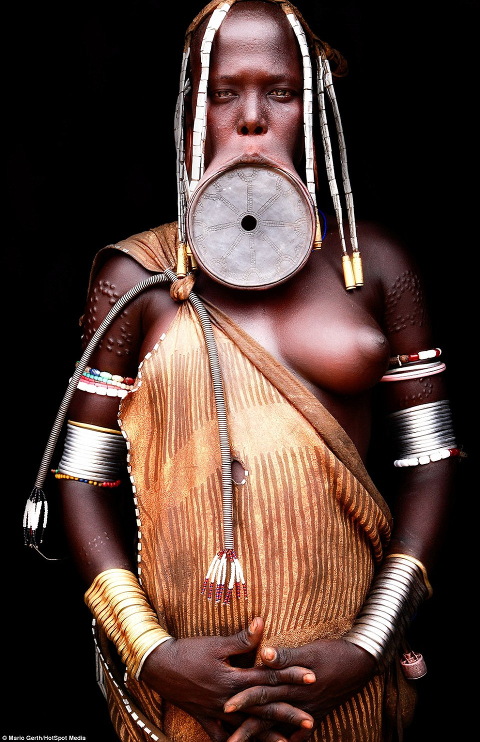 Khi những tới tuổi dậy thì, các bé gái sẽ phải nhổ bỏ hàm dưới, khoét 1 lỗ trên môi và nhét đĩa đất sét vào đó. Đường kính của chiếc đĩa sẽ tăng theo thời gian. (Nguồn: Dailymail.co.uk)