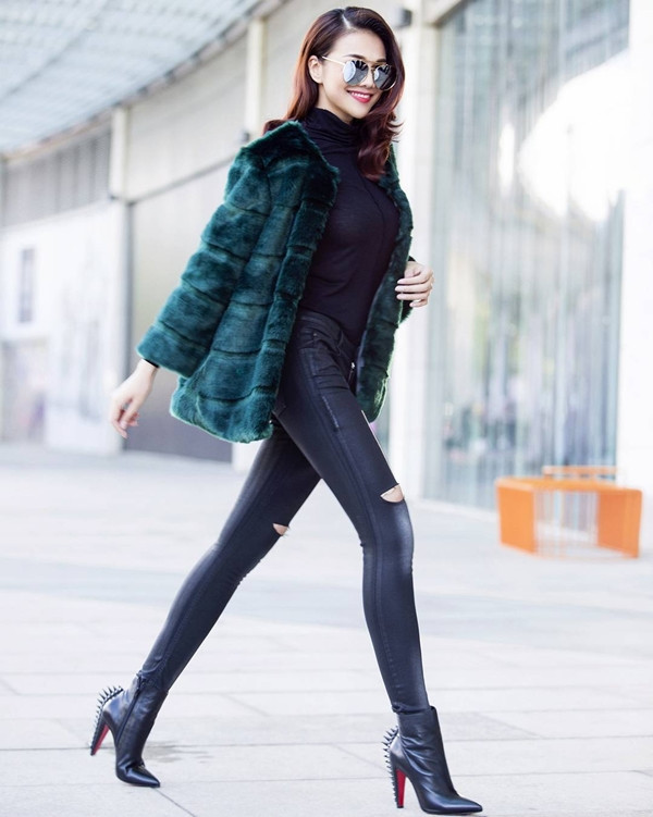 Khoe dáng nuột nà với bộ cánh tuyền đen ôm sát, Thanh Hằng gây ấn tượng khi chọn áo khoác lông màu xanh lá làm điểm nhấn sành điệu. Kính mắt tráng gương và bốt cổ lửng đính đinh tán của Louboutin là những phụ kiện chấm phá hoàn hảo cho phong cách thời thượng của siêu mẫu. 