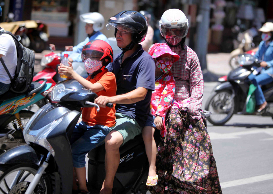 Nhiều người lớn và trẻ em đều được bịt kín toàn thân khi lưu thông trên đường phố Hà Nội. (Ảnh: Quý Trung/TTXVN) 
