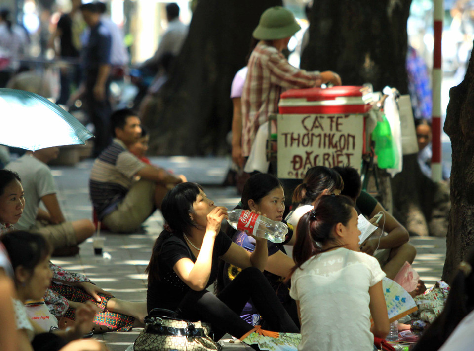 Tại cổng bệnh viện phụ sản Trung ương (Phố Tràng Thi – Hà Nội) những bóng mát là nơi tránh nắng tốt nhất cho người nhà bệnh nhân. (Ảnh: An Đăng/TTXVN) 