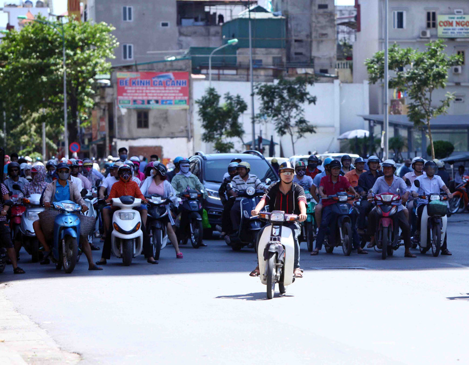 Chờ đèn đỏ trên tuyến phố Bạch Mai, người dân tận dụng tối đa bóng mát để ẩn nấp cái nắng gay gắt. (Ảnh: Quý Trung/TTXVN) 
