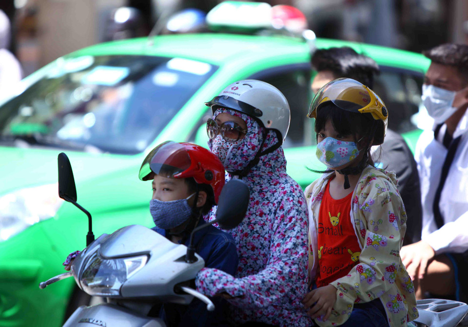 Nhiều người lớn và trẻ em đều được bịt kín toàn thân khi lưu thông trên đường phố Hà Nội. (Ảnh: Quý Trung/TTXVN) 