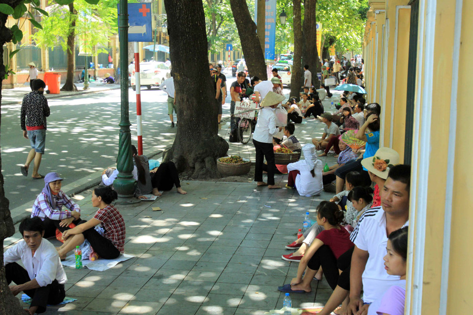 Tại cổng bệnh viện phụ sản Trung ương (Phố Tràng Thi – Hà Nội) những bóng mát là nơi tránh nắng tốt nhất cho người nhà bệnh nhân. (Ảnh: An Đăng/TTXVN) 