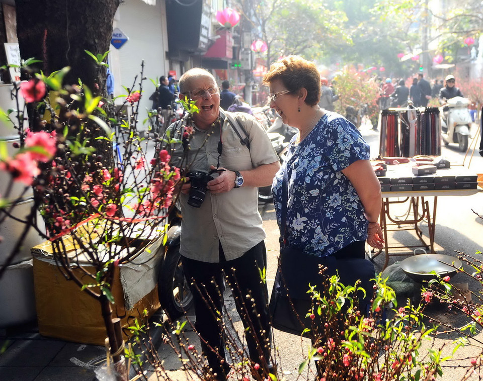 Du khách quốc tế thích thú với khung cảnh chợ hoa Tết Hàng Lược. (Ảnh: Minh Đức/TTXVN) 