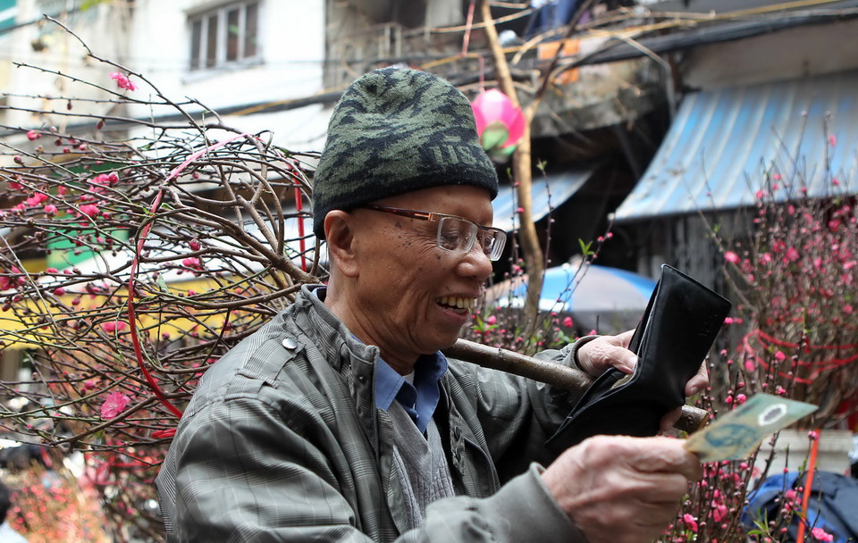 Vui mừng khi tìm mua được cành đào ưng ý. (Ảnh: Quốc Khánh/TTXVN)