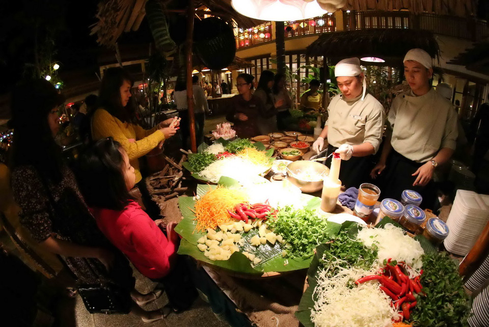 Khách du lịch tham quan và thưởng thức ẩm thực tại phiên Chợ quê ngày Tết xưa. (Ảnh: Trần Lê Lâm/TTXVN) 