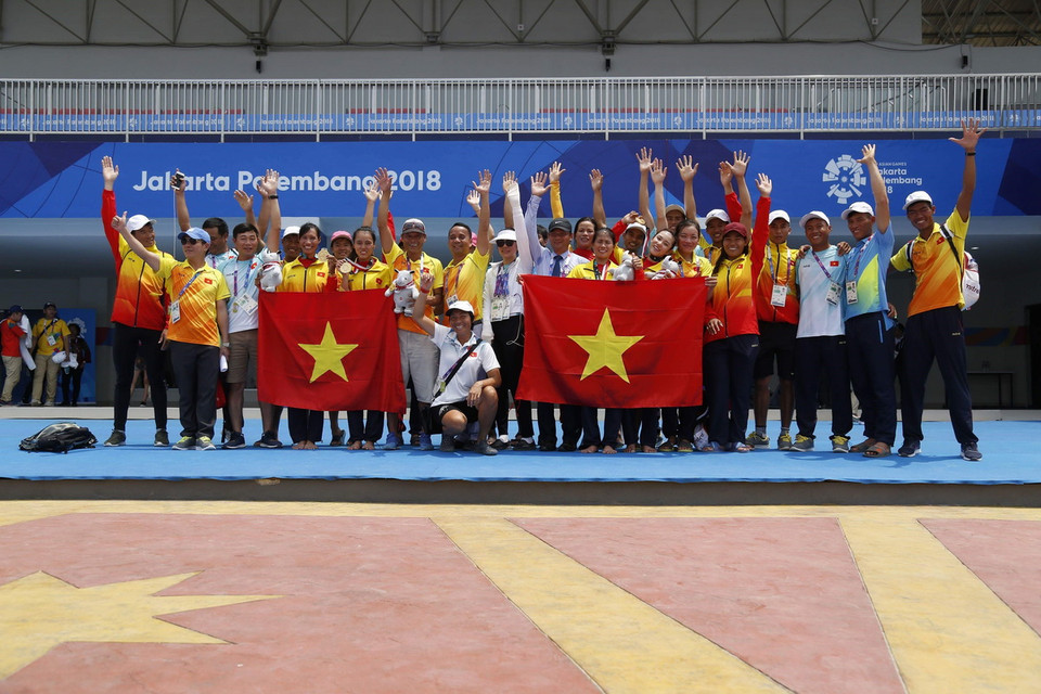 Các thành viên đoàn thể thao Việt Nam chúc mừng các cô gái vừa giành huy chương vàng nội dung rowing. (Nguồn: TTXVN phát)