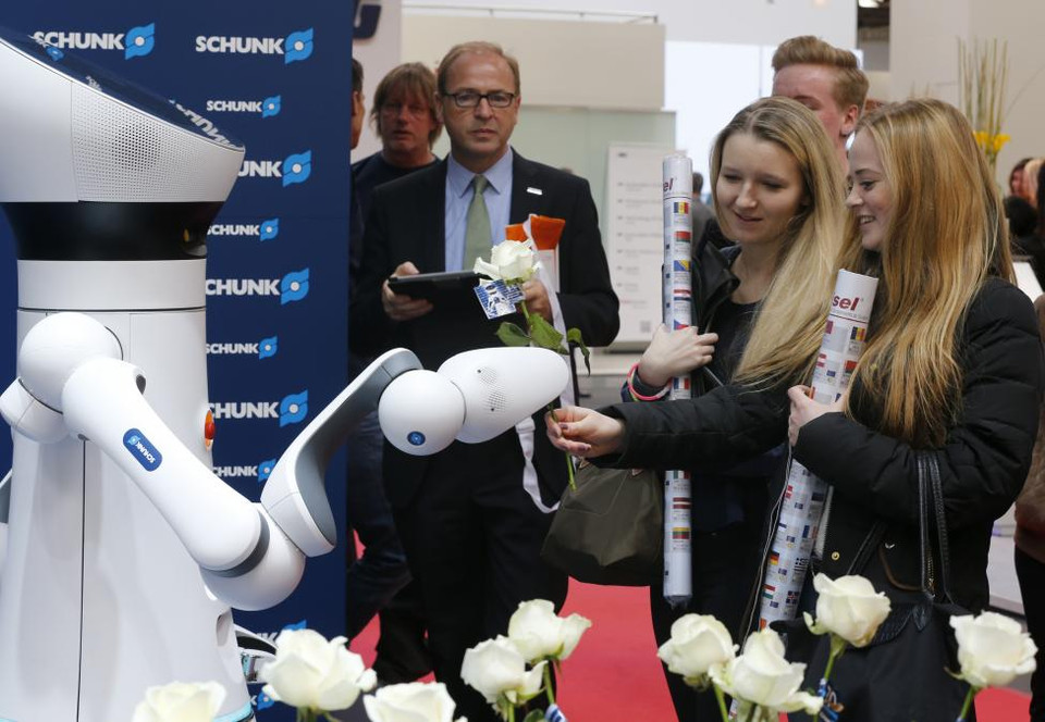 Một cánh tay robot tặng hoa cho các cô gái tại các gian hàng của hãng SCHUNK tại hội chợ. (Nguồn: Reuters)