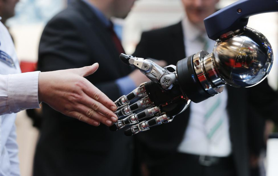 Khách tham quan bắt tay một cánh tay robot ở hội chợ. (Nguồn: Reuters) 