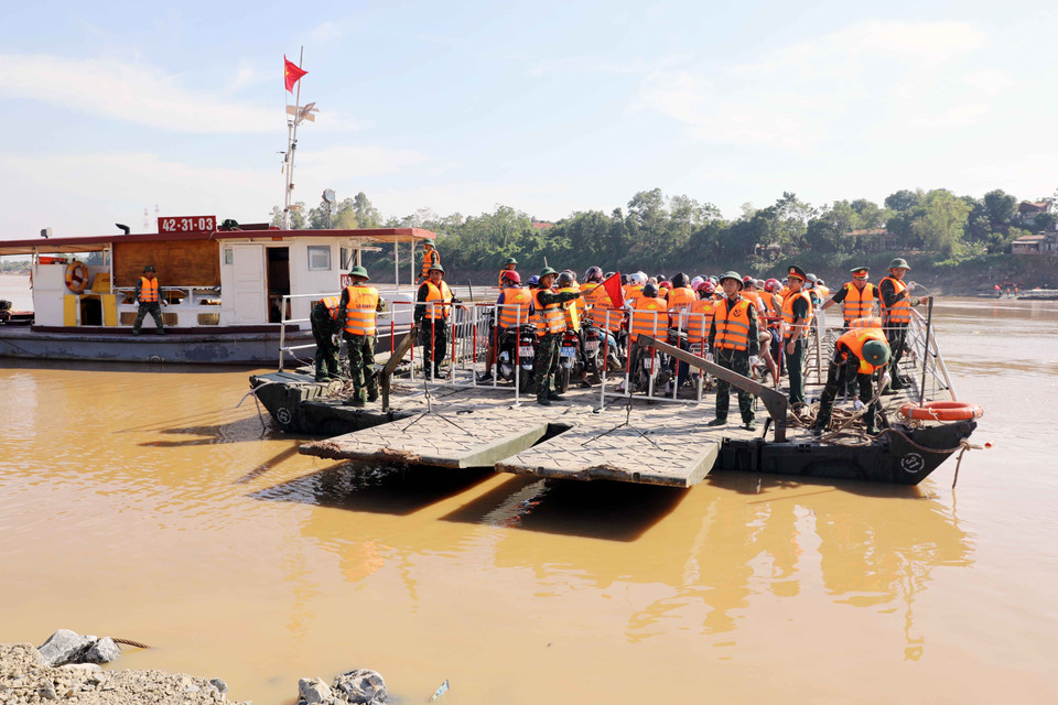 Trước khi phà di chuyển, các lực lượng thực hiện đóng rào chắn nhằm bảo vệ an toàn cho người dân trên phà. (Ảnh: Tạ Toàn/TTXVN)