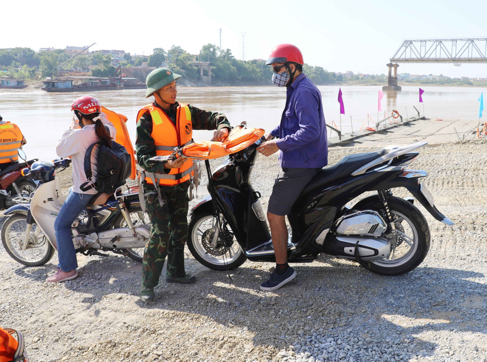 Các chiến sỹ thuộc lực lượng Công binh 249 và các chiến sỹ thuộc lực lượng quân đội tỉnh Phú Thọ hướng dẫn, hỗ trợ người dân khi tham gia lưu thông qua phà, đảm bảo đúng quy định. (Ảnh: Tạ Toàn/TTXVN)