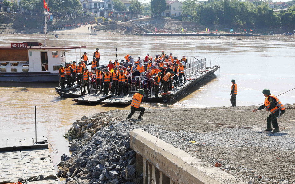 Các lực lượng chức năng vận hành chuyến phà đầu tiên đưa người dân và các phương tiện qua sông Hồng được di chuyển từ phía xã Hương Nộn sang xã Bản Nguyên thay thế cầu phao tạm dừng hoạt động do nước sông Hồng dâng cao. (Ảnh: Tạ Toàn/TTXVN)