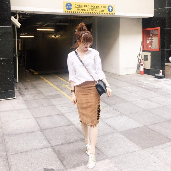 Yến Nhi nhấn nhá vẻ nữ tính với chân váy da lộn màu camel và sơ mi trắng. Nữ ca sĩ mix trang phục cùng giày thể thao ánh kim, tạo nét lôi cuốn.