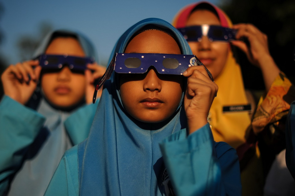 Các học sinh Malaysia đeo kính để quan sát hiện tượng nhật thực một phần ở Kuala Lumpur ngày 9/3. (Nguồn: AFP/TTXVN)