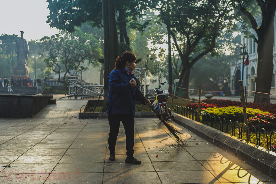 Ở phía khác, vẫn có những người cần mẫn để Hà Nội sạch hơn, đẹp hơn những ngày đầu năm mới. (Ảnh: Hoàng Long-Võ Phương/Vietnam+)