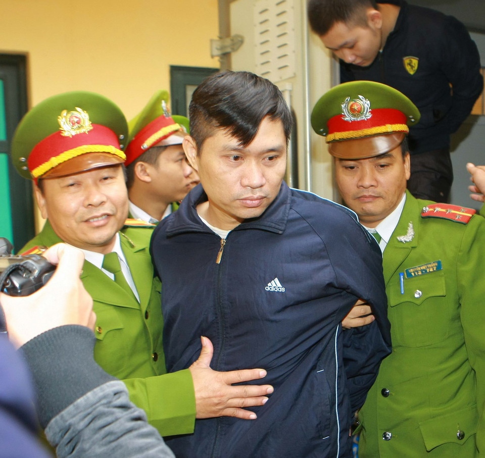  Cảnh sát dẫn giải bị cáo Nguyễn Mạnh Tường (phía trước) và Đào Quang Khánh (áo đen, phía sau) vào phòng xét xử.