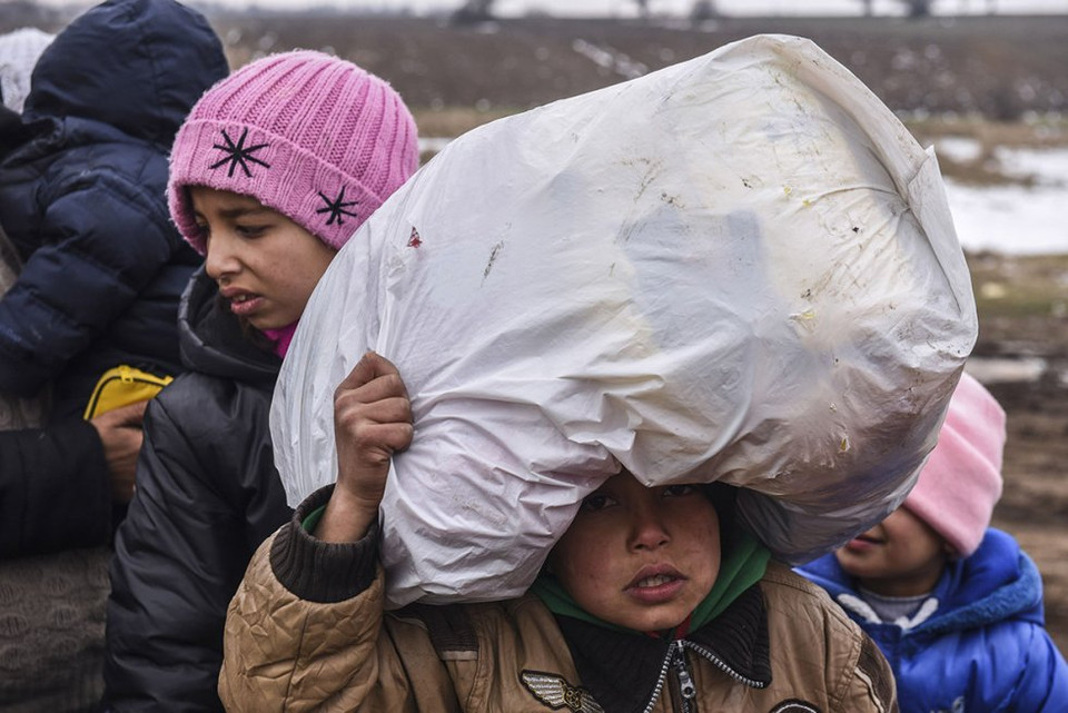 Một em bé đang phải vác đồ, chờ tới lượt kiểm tra an ninh sau khi vượt biên giới Macedonia vào Serbia. (Nguồn: Reuters)