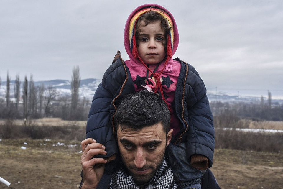 Ông bố cõng con trong dòng người xếp hàng chờ kiểm tra an ninh. (Nguồn: Reuters)