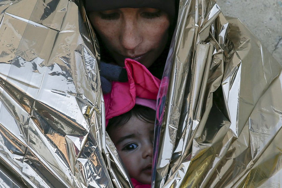 Hai mẹ con nằm trong chăn giữ nhiệt, chờ tàu tới Croatia. (nguồn: Reuters)