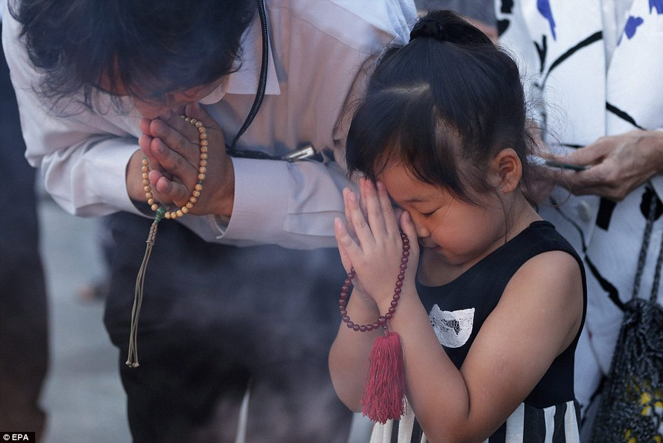 Một bé gái cũng cầu nguyện cho các nạn nhân. (Nguồn: Dailymail)