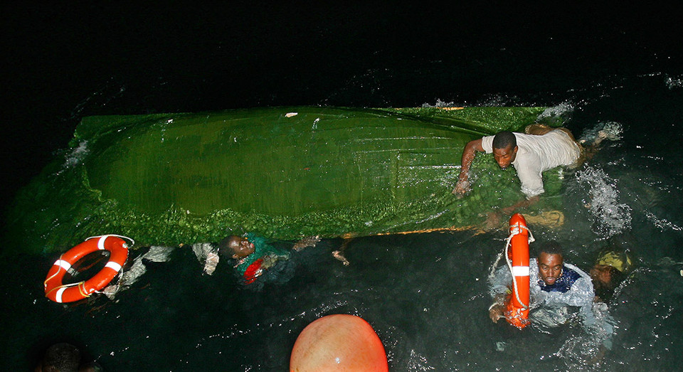 Người nhập cư đang bám vào các phao cứu sinh sau khi thuyền của họ bị lật. (Nguồn: Reuters)